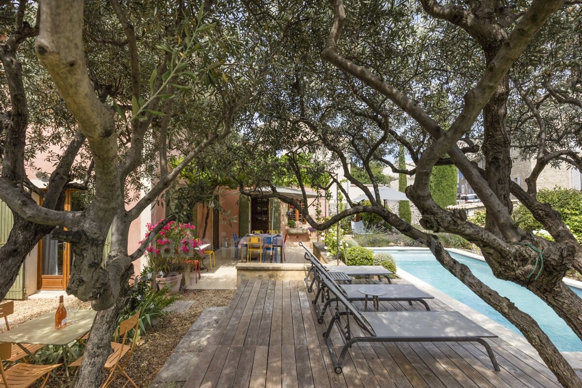 A swimming pool is surrounded by trees and chairs