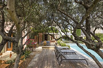 A swimming pool is surrounded by trees and chairs