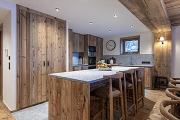 A kitchen with wooden cabinets and a clock on the wall
