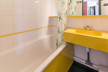 A bathroom with a yellow sink and bathtub