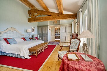 A bedroom with a large bed and a red rug
