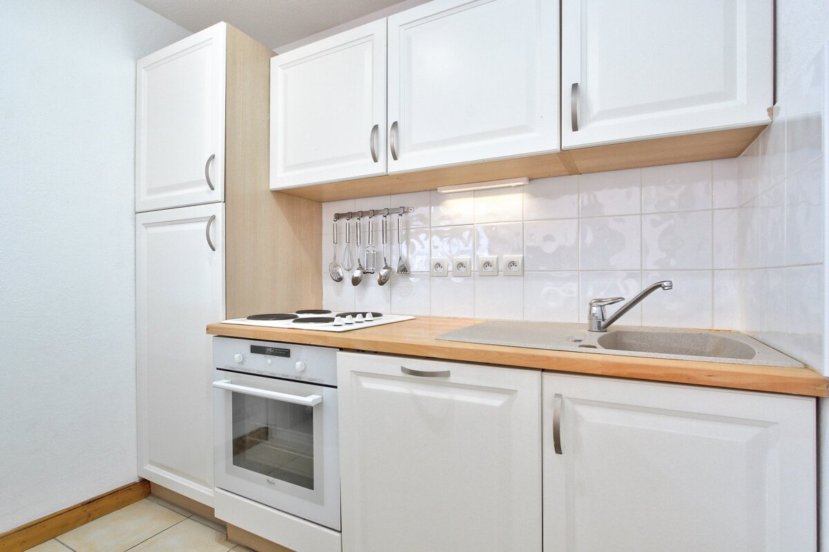 A kitchen with white cabinets and a stove top oven