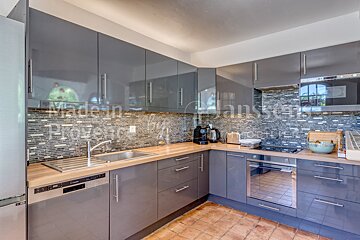 A kitchen with gray cabinets and a stainless steel dishwasher