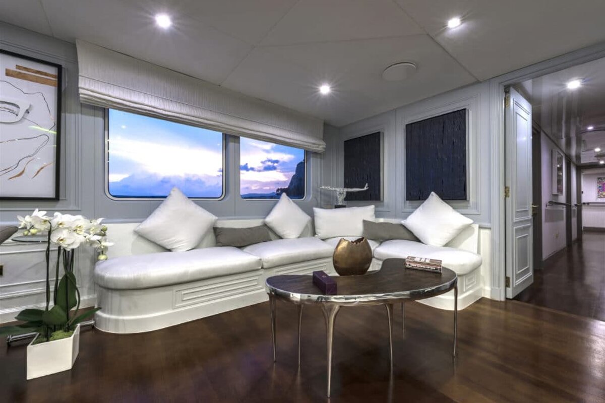 A living room with white furniture and a table with a vase of flowers on it