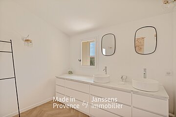 A bathroom with two sinks and two mirrors made in provence by immobilier