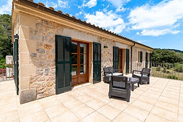 A stone building with a balcony with chairs and a table