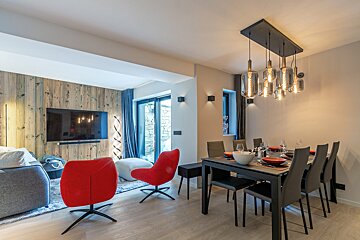 A dining room with a table and chairs and a flat screen tv