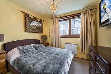 A bedroom with a bed a dresser and a flat screen tv