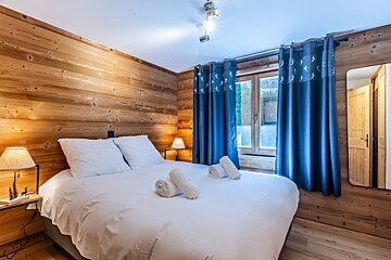 A bedroom with a large bed and blue curtains