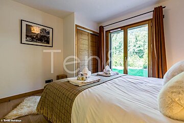 A bedroom with a bed and a picture on the wall that says ten80 holidays