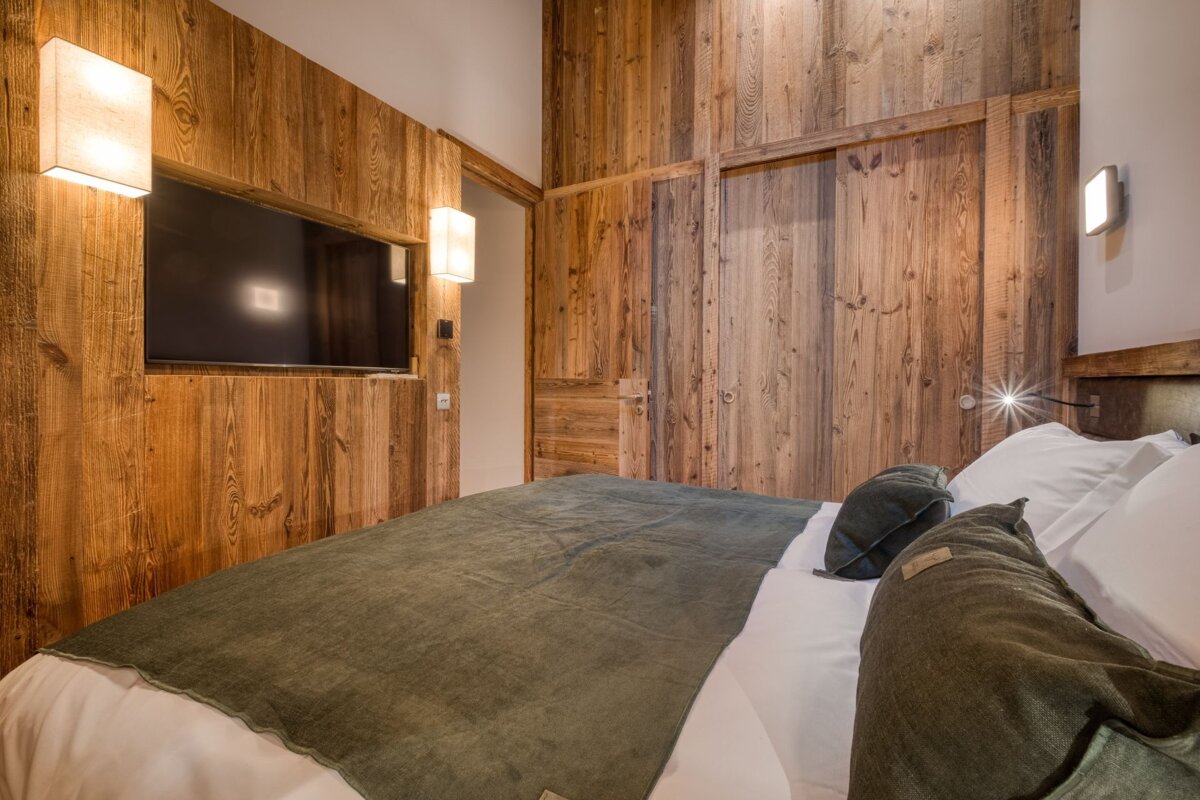 A bedroom with wood paneling and a flat screen tv