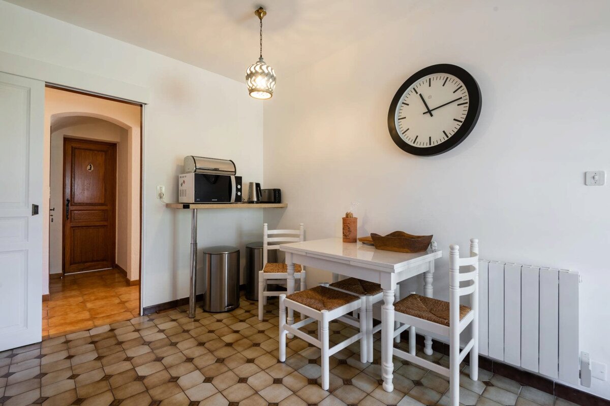 A kitchen with a table and chairs and a clock on the wall