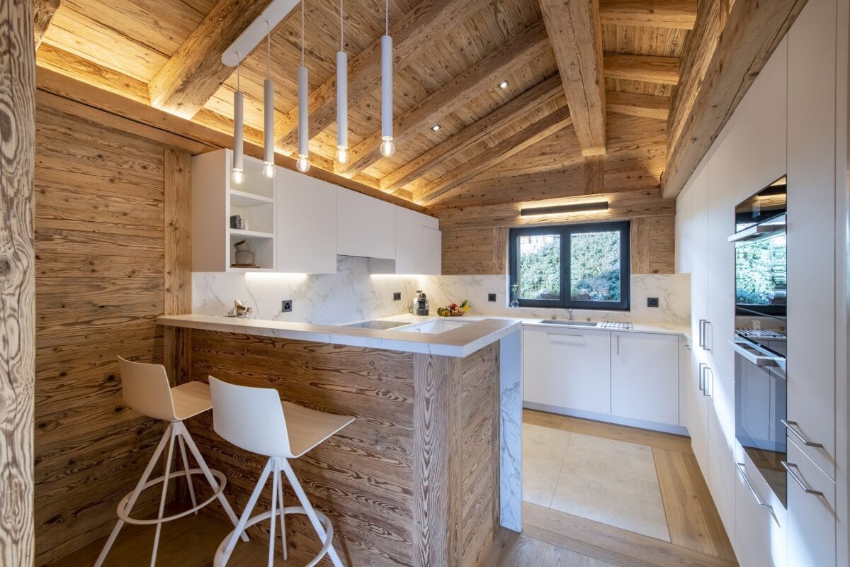 A kitchen with a wooden ceiling and white cabinets