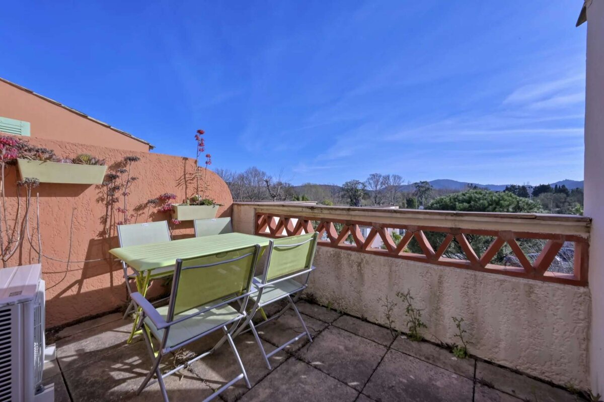 A table and chairs on a balcony with mountains in the background