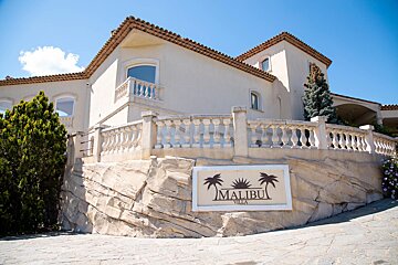 A large white building with a sign that says malibu villa