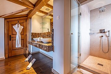A bathroom with two sinks and a walk in shower
