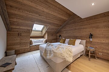 A bedroom with a bed and a window in the corner