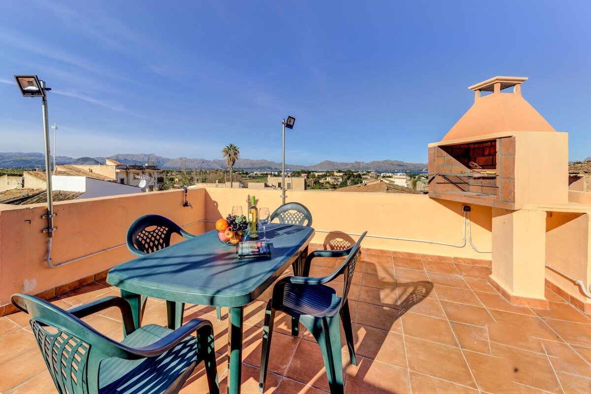 A table and chairs on a rooftop with mountains in the background