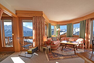 A living room with a couch and a table with mountains in the background