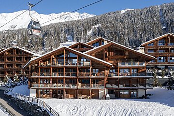 A ski lift is pulling skiers up to a ski resort