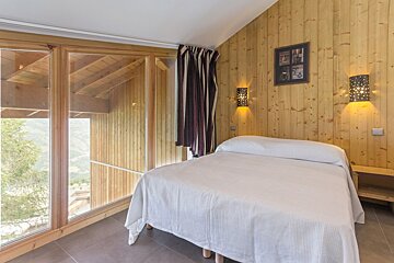 A bedroom with wood paneling and a large bed