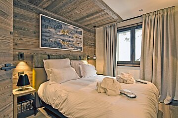 A bedroom with a painting on the wall above the bed