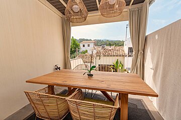 A wooden table with wicker chairs and a plant on it
