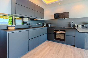 A kitchen with black cabinets and a stainless steel oven