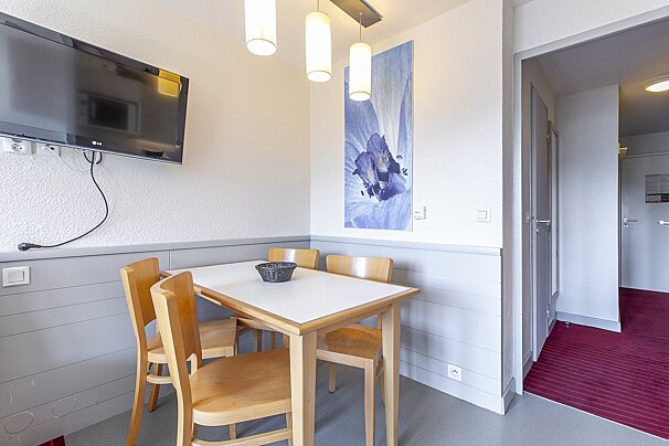 A small dining room with a table and chairs and a flat screen tv