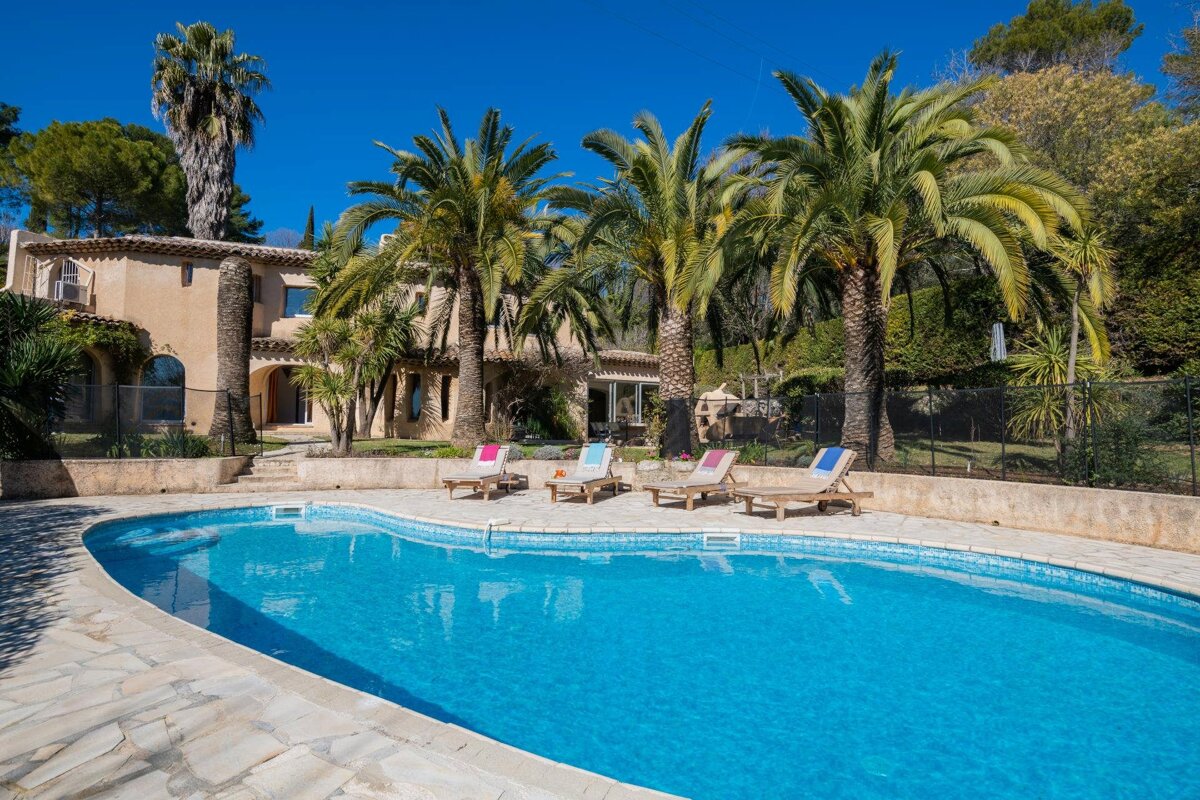 A large swimming pool surrounded by palm trees and chairs