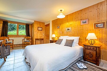 A bedroom with a bed and two lamps and a bag with the letter b on it