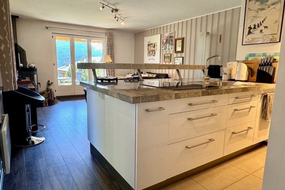 Kitchen island with granite countertops looking toward a cozy living area with glass doors.