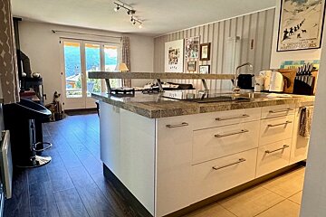 Kitchen island with granite countertops looking toward a cozy living area with glass doors.