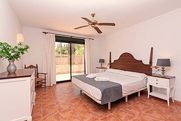 A bedroom with a large bed and a ceiling fan
