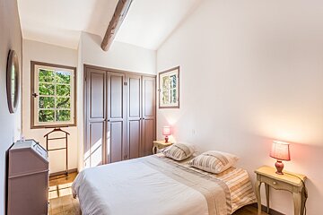 A bedroom with a bed and two lamps