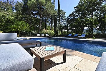 A table with a book on it sits next to a swimming pool