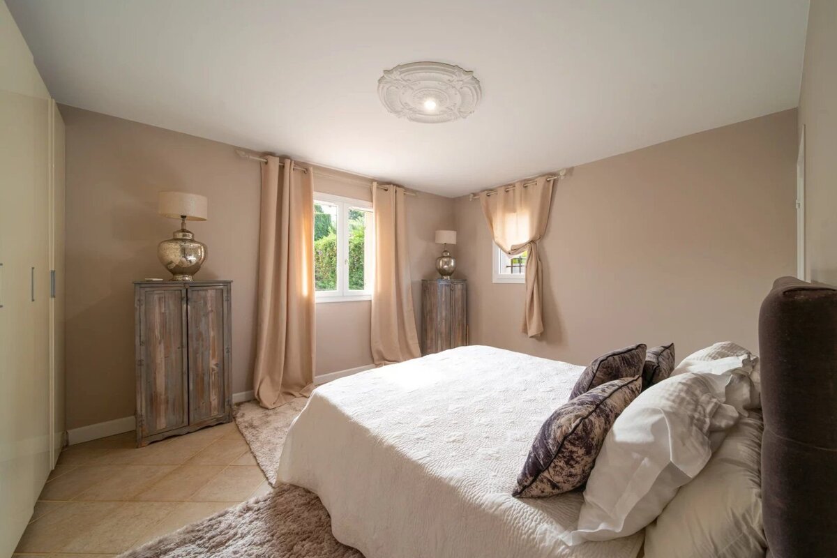 A beige-colored bedroom with a double bed, decorated in a rustic style.