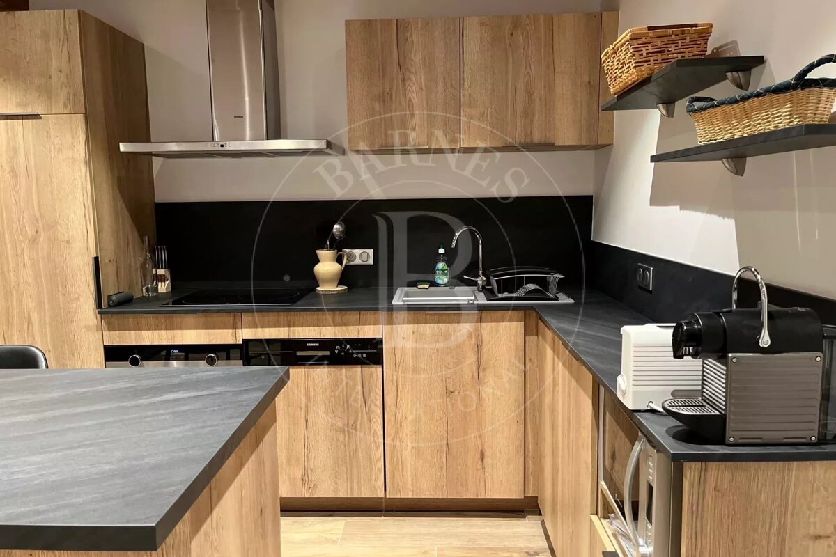 Modern kitchen with light wood cabinets, dark countertops, integrated appliances, and a kitchen island.