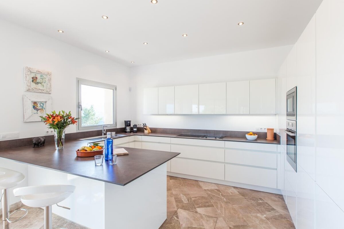 A kitchen with white cabinets and black counter tops