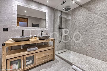 A bathroom with two sinks and a walk in shower