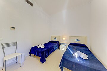 A bedroom with two twin beds and a chair