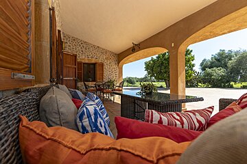 A patio with a table and chairs and pillows on it
