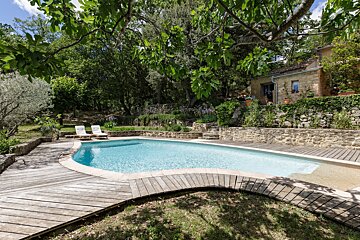 A large swimming pool surrounded by trees and a wooden deck