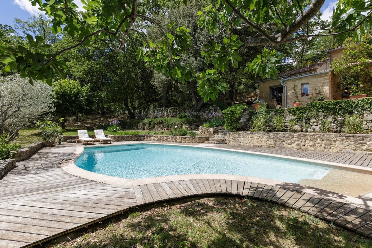 A large swimming pool surrounded by trees and a wooden deck