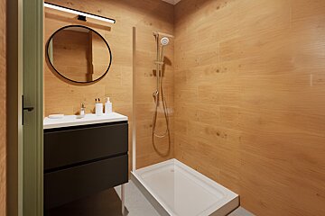 A modern bathroom with warm wood-look tiled walls, featuring a dark vanity, round mirror, sleek light, and a walk-in shower with a white tray.