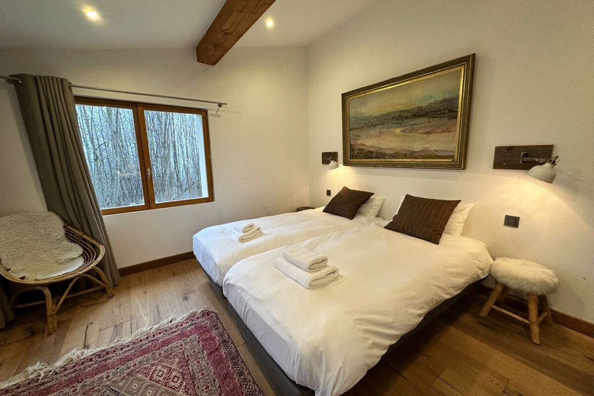 A bedroom with two beds and a painting on the wall