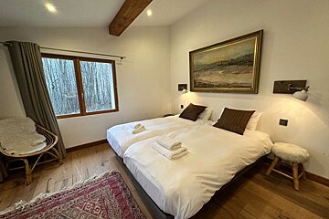 A bedroom with two beds and a painting on the wall