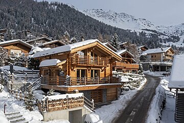 A snowy landscape with a wooden house in the foreground