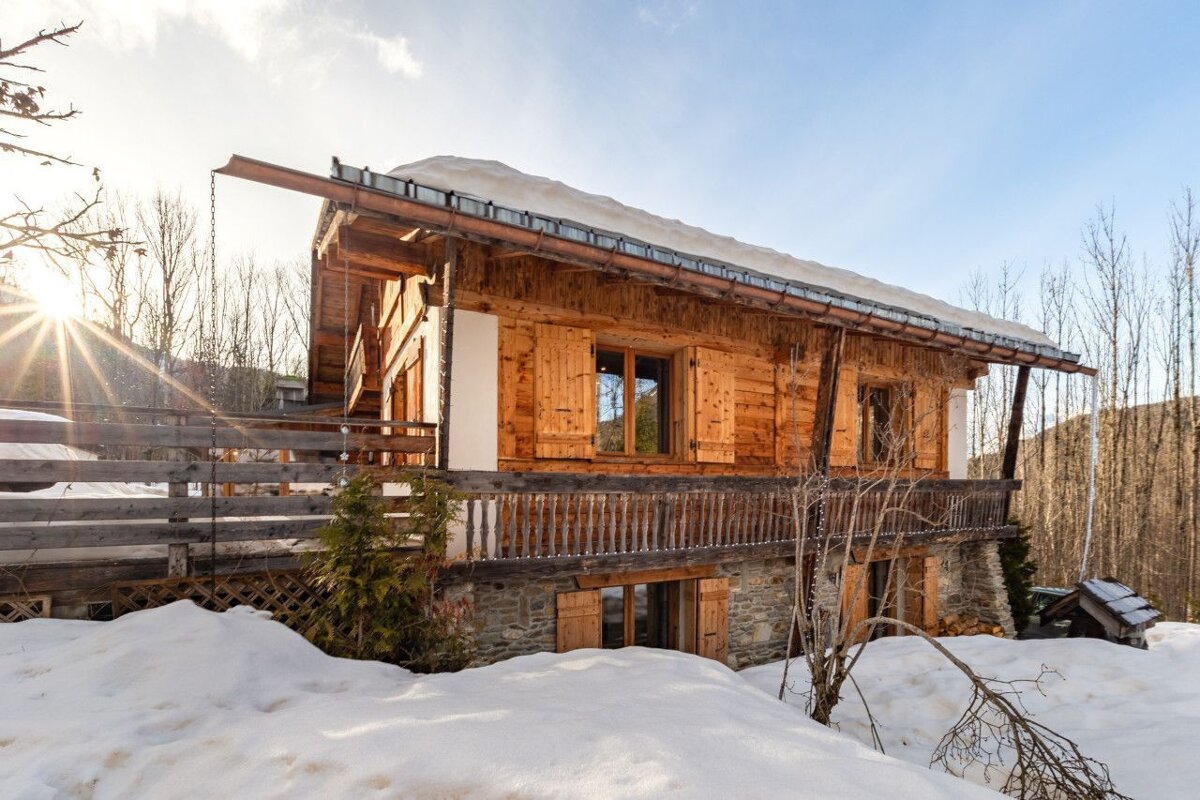 The sun is shining brightly on a snowy house