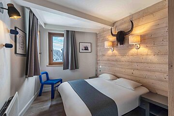 A small bedroom with a bed and a blue chair